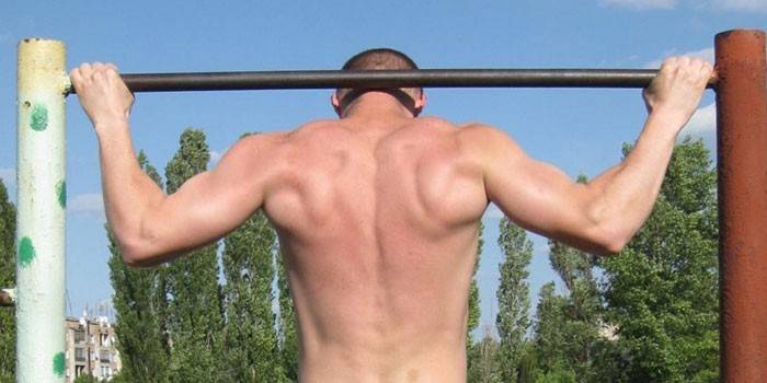 Um homem executa um pull-up com um bar atrás da cabeça