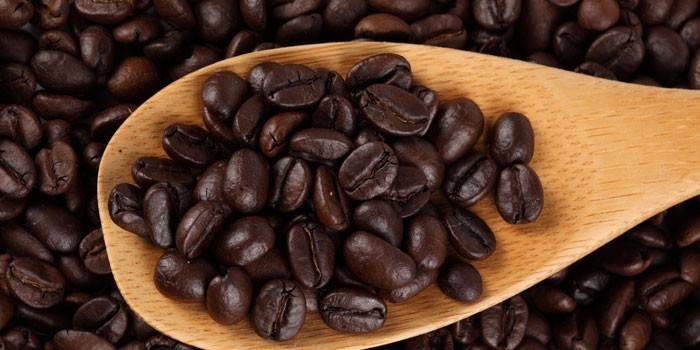 Granos de café tostados fuertes sobre una espátula de madera.