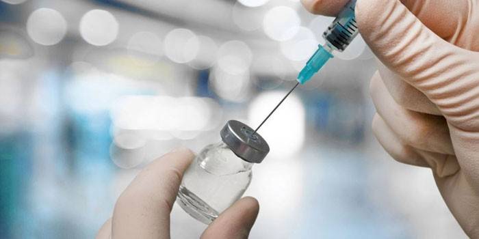 Bir doktorun elinde ilaçla birlikte şırınga ve şişe