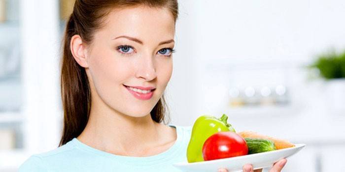 Niña sostiene un plato con verduras en la mano