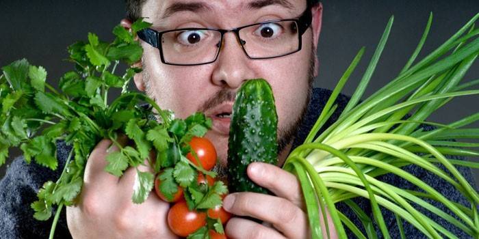 Homem com legumes e ervas em suas mãos.