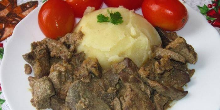 Hígado de cerdo con puré de papas y tomates en un plato