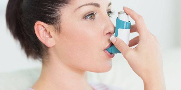 Chica con un inhalador en la boca.