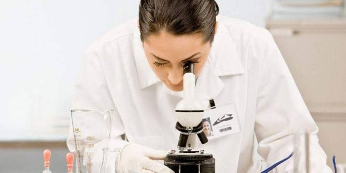 Laboratórny technik pri pohľade cez mikroskop