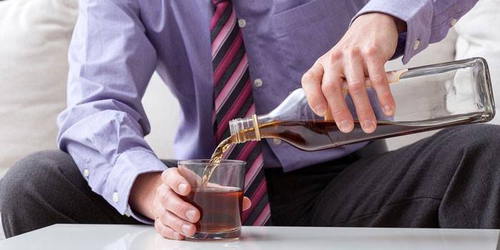 Mężczyzna nalewa whisky do szklanki