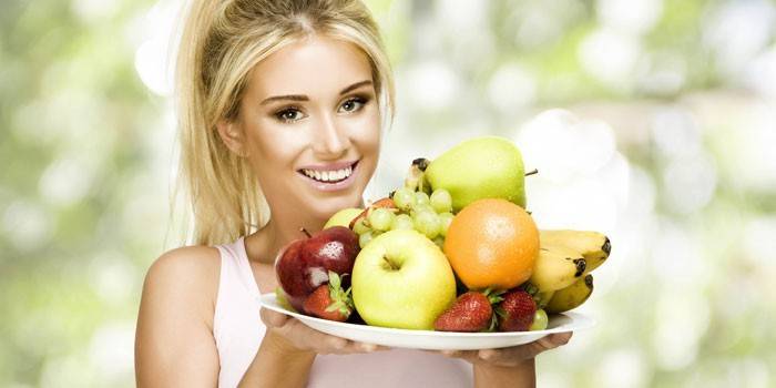 A menina prende um prato com frutas e bagas.