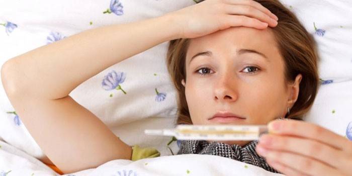A menina encontra-se na cama com um termômetro na mão