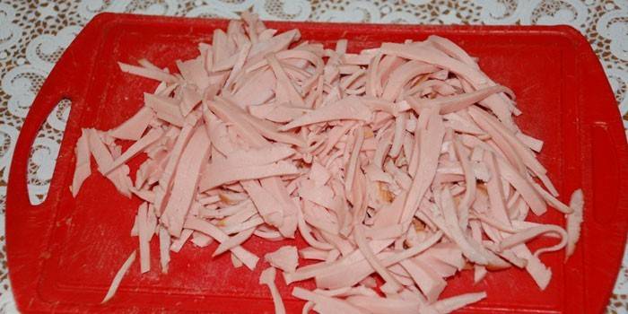Julienne cozido salsicha em uma placa de corte