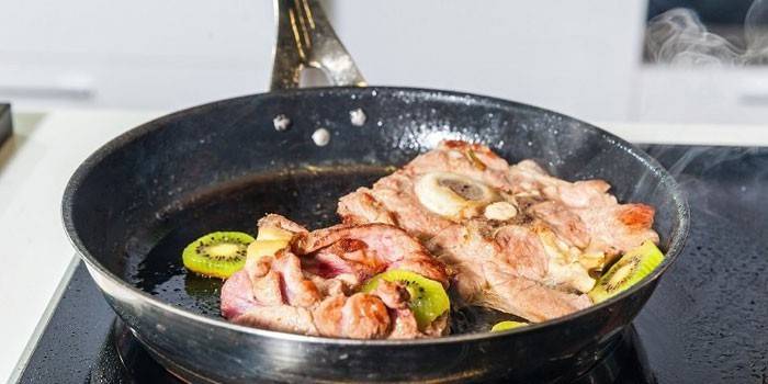 Carne frita com kiwi em uma panela
