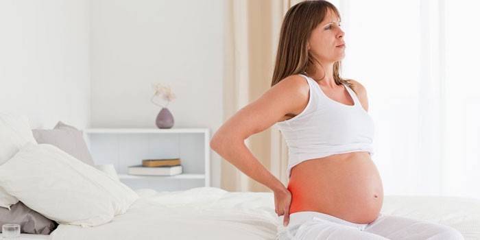 Niña embarazada sentada en la cama