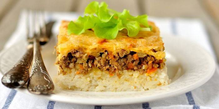 Un trozo de cazuela de arroz y carne picada bajo una tapa de queso
