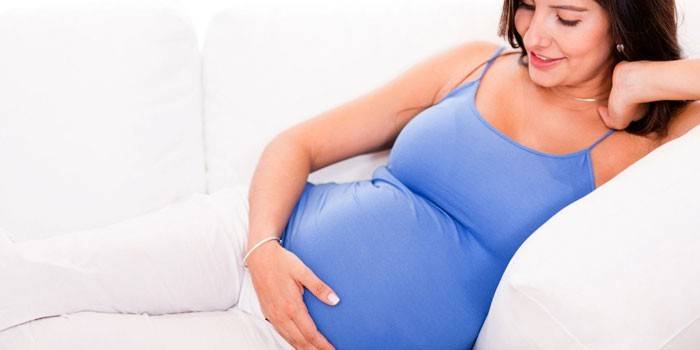 La niña embarazada yace en un sofá