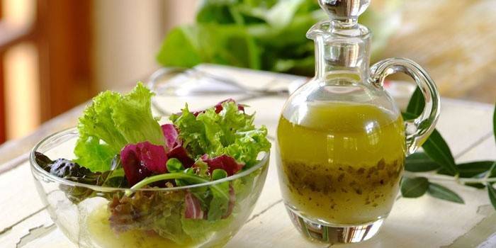 Salada de folhas em uma tigela e molho pronto para se vestir