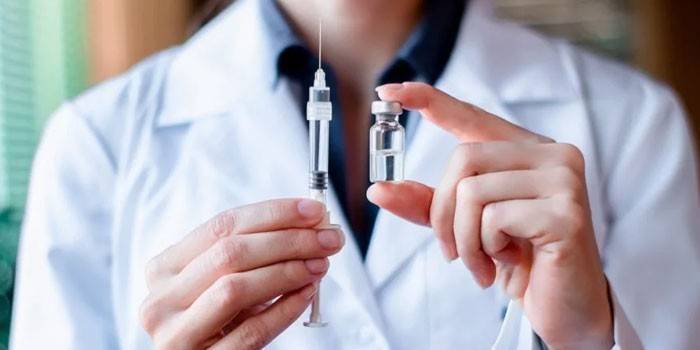 Una vacuna y una jeringa en manos de un médico.