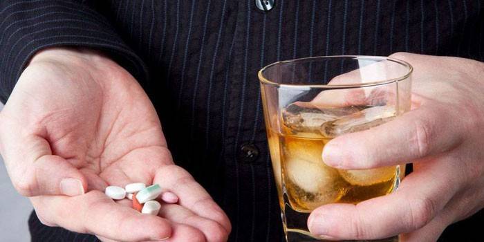 Mężczyzna trzyma lek i whisky w szkle