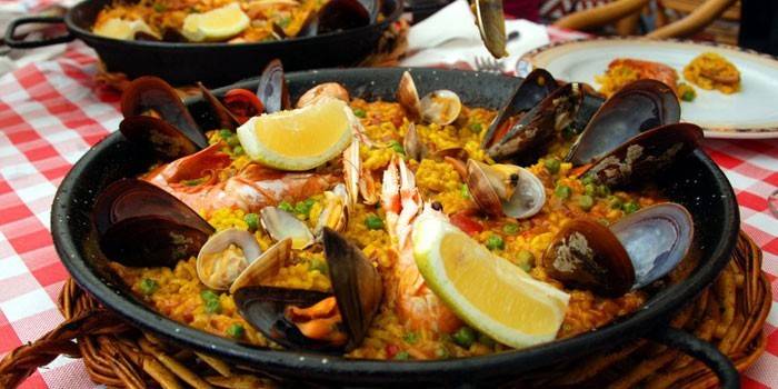Paella pronta com frutos do mar e limão em uma panela