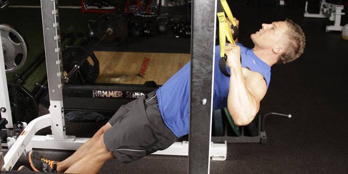 Um homem executa pull-ups reversos em loops