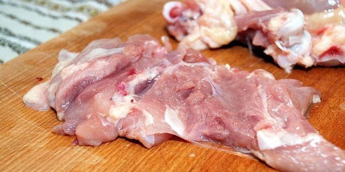 Muslo de pollo deshuesado sobre una tabla para cortar
