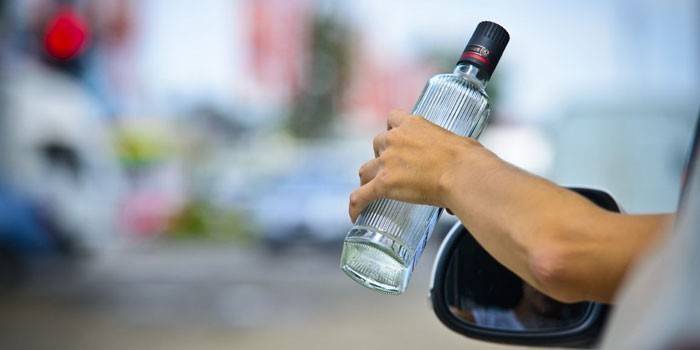 Garrafa de vodka nas mãos de um motorista de carro