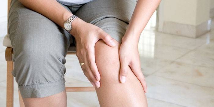 Una mujer sostiene su rodilla con las manos.