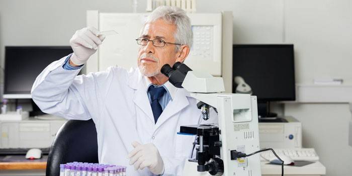 Muž lekár pri pohľade na laboratórne sklo v ruke