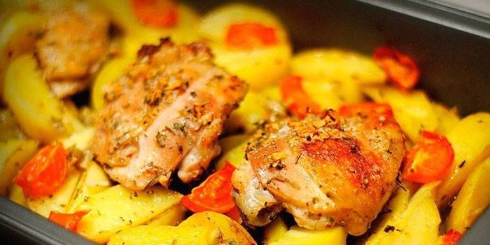 Muslos de pollo al horno con papas en una bandeja para hornear