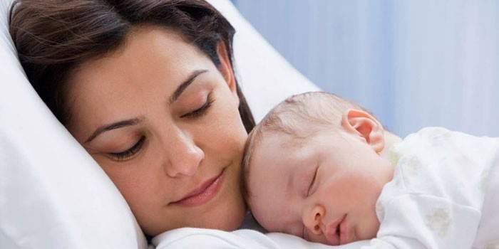 Um bebê dorme no peito da mãe