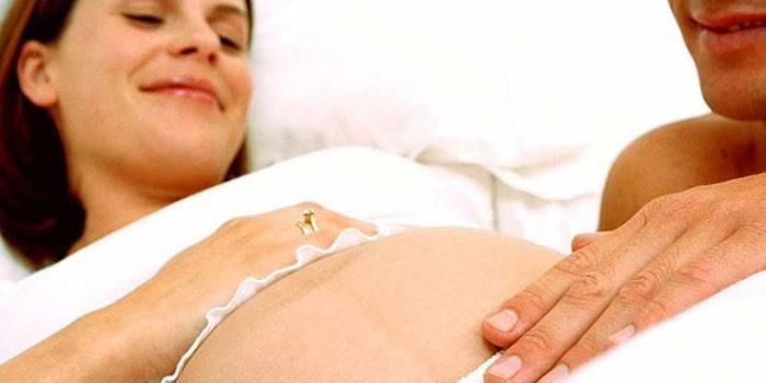 Muž drží ruku na bruchu tehotného dievčaťa