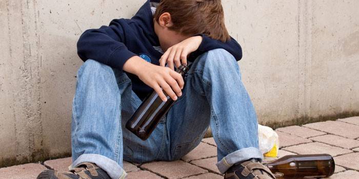 Adolescente con una botella de cerveza vacía en la mano