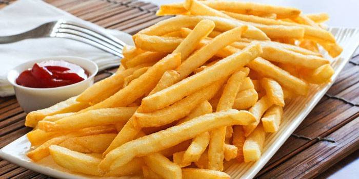 Un plato de papas fritas al horno con salsa de tomate