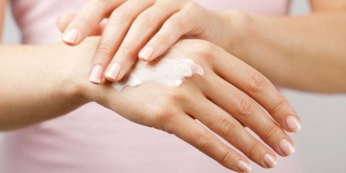 Garota coloca creme nas mãos dela