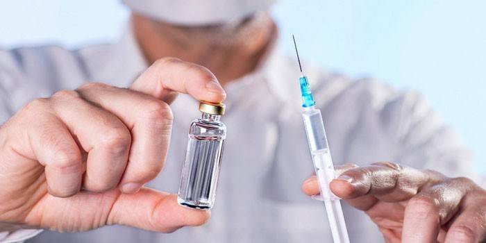 Medic drží striekačku a fľašu s liekom