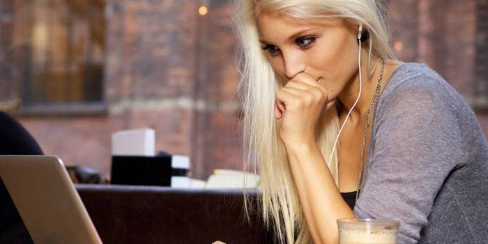 Niña sentada en una computadora portátil en auriculares