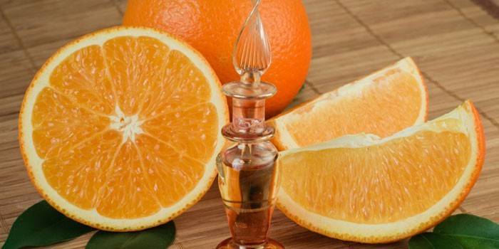 Óleo essencial de laranja em uma garrafa e laranja picada