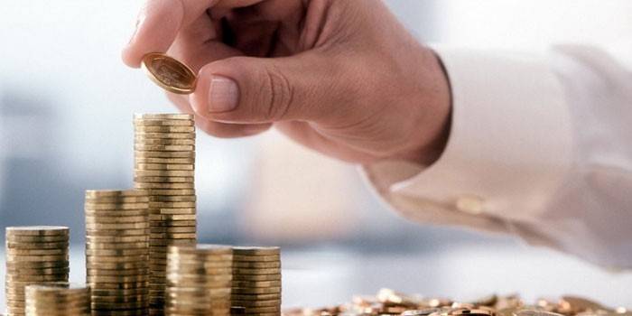 Hombre alineando monedas de metal en una columna