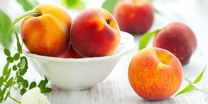 Pêssegos maduros em um prato e em uma mesa