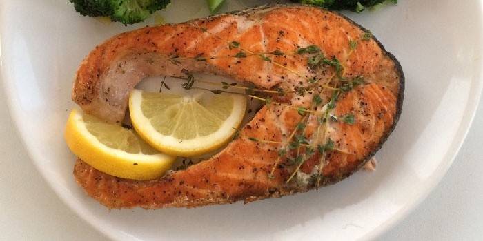 Doska s pripraveným steakom z lososa, citrónom a bylinkami