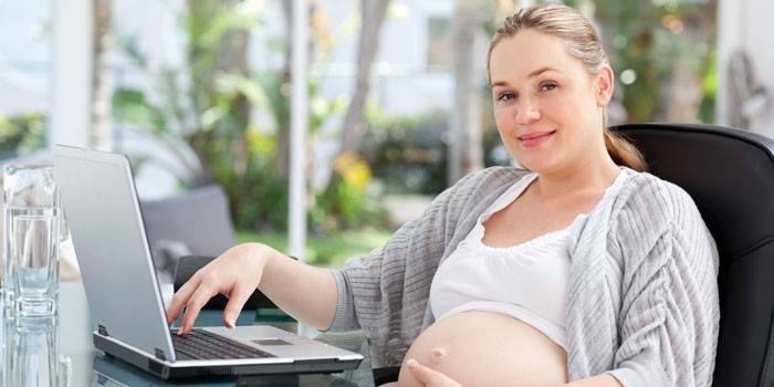 Menina grávida em um laptop