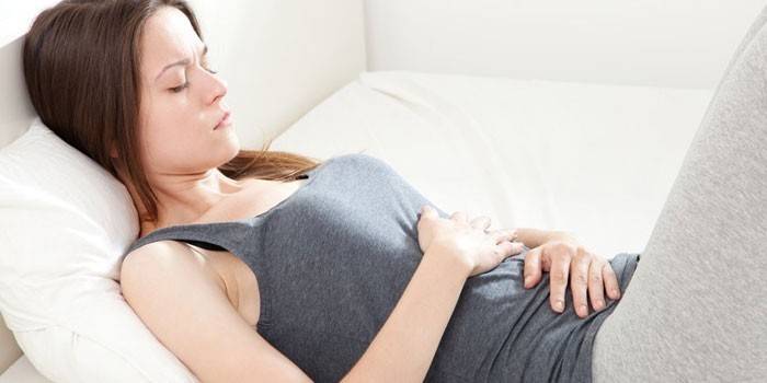 La niña se acuesta en la cama y se pone las manos sobre el estómago.