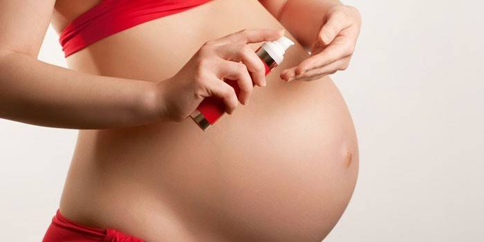 Menina grávida com creme nas mãos dela