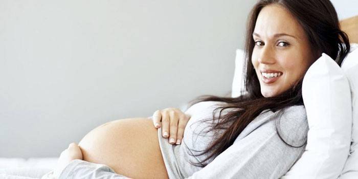 Menina grávida encontra-se na cama