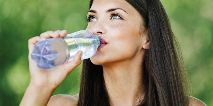 Niña bebe agua de una botella