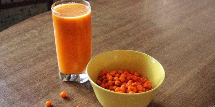 Suco de espinheiro mar em um vidro e bagas de espinheiro mar em um prato