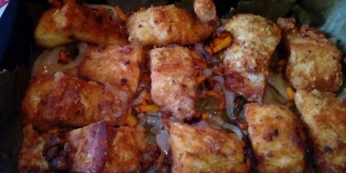 Rodajas de lucio con verduras en una bandeja para hornear