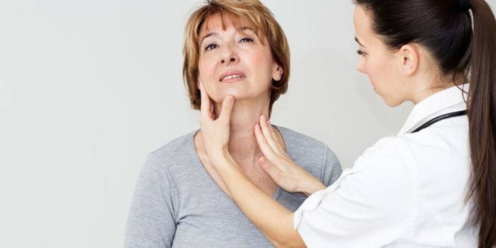 Um médico examina a glândula tireóide de uma mulher