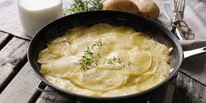 Gratinado de papas al horno en salsa de crema agria en una sartén