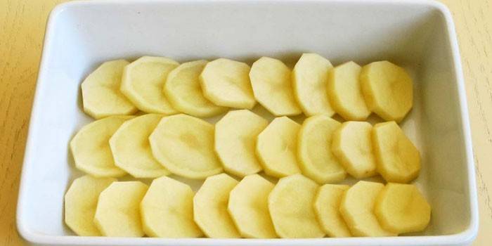 Uma camada de fatias de batata crua em fatias