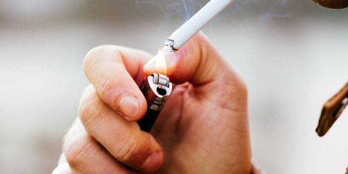 Un hombre enciende un cigarrillo.
