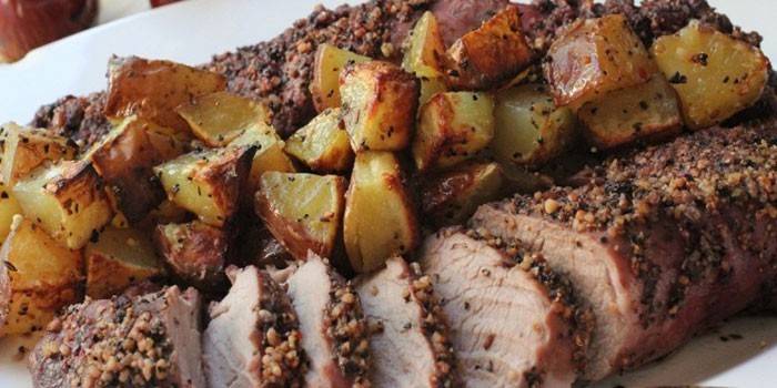 Cerdo hervido con rodajas de papas al horno en un plato