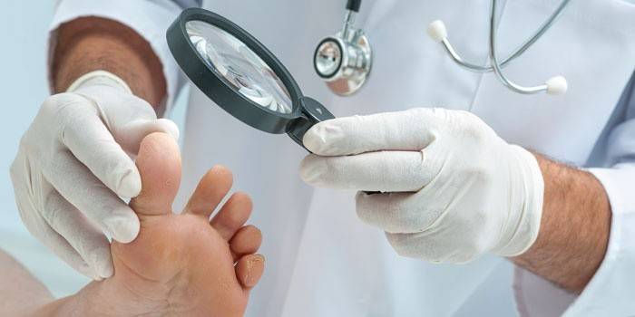 El médico examina las piernas del paciente.